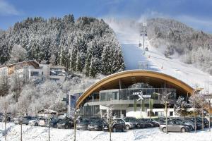 a building with a bunch of cars parked in the snow at Spa Apartments - next to AreitXpress Liftstation in Zell am See