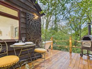 eine Terrasse mit einem Tisch, Stühlen und einem Grill in der Unterkunft Lake View Lodge & Outdoor Bath in East Grinstead