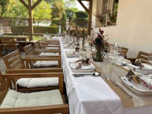 a long table with white tables and chairs with plates and flowers at life-stegersbach Suites in Stegersbach