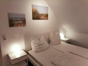 a bedroom with a bed with two nightstands and two pictures at Meeresfeeling in Horumersiel in Horumersiel