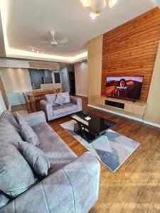 a living room with a couch and a flat screen tv at Lucky 7 Homestay - Utama Court in Sandakan