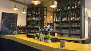 a bar with a yellow counter with bottles of alcohol at Hôtel Le Paris Brest in Lens