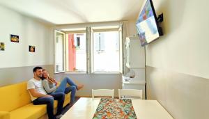 a man and woman sitting on a yellow couch in a room at Strategico tra i MERCATiNi di Natale! zona centro storico - stazione in Trento