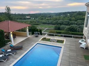 a backyard with a swimming pool and a patio with chairs at Villa Oasis Cypress in Čilipi