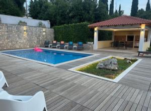 a backyard with a swimming pool and a wooden deck at Villa Oasis Cypress in Čilipi