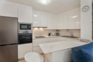 cocina con armarios blancos y sofá azul en Apartamento Estrella, en Candelaria