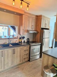 a kitchen with wooden cabinets and stainless steel appliances at Le Domaine Riverin in Pohénégamook