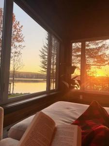 a bedroom with two windows and a bed with a book at Le Domaine Riverin in Pohénégamook +15 photos
