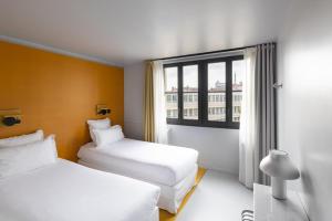 Una habitación de hotel con dos camas y una ventana. en The People Lyon, en Lyon