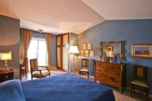 een slaapkamer met een blauw bed, een dressoir en een spiegel bij Argentario Rooms - By The Sea in Porto Santo Stefano