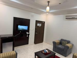 a living room with a tv and two chairs and a table at شقق الاوفاز للشقق المخدومة--إقتصادي in Qal'at Bishah