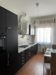 een keuken met zwarte kasten en een tafel met een eetkamer bij Casa Vacanze Ilenia in Marina di Montemarciano