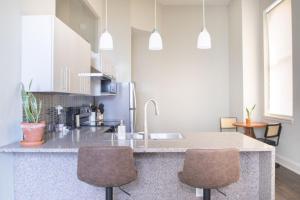 una cucina con lavandino e bancone con due sedie di Downtown Luxury 1BR Loft a Milwaukee Altre 10 foto