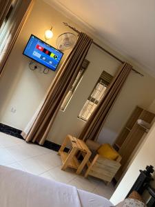 a living room with a couch and a tv on the wall at White Ash Studios Komamboga in Kampala