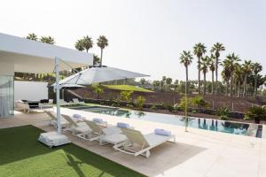 einem Pool mit Stühlen und einem Sonnenschirm neben einem Haus in der Unterkunft Villa Palm Abama Golf in Playa de San Juan