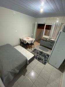 een slaapkamer met een bed en een tafel en een keuken bij AP completo a 5 min da Praia, Itapema-SC in Itapema