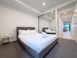 a bedroom with a large white bed and a mirror at Cosy Convenience 2BR APT in Castle Hill in Castle Hill