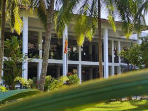 a building with palm trees in front of it at BREATHE Collections Habaraduwa in Habaraduwa