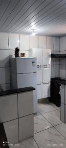 a kitchen with white cabinets and a refrigerator at Kitnet in Itaparica Town