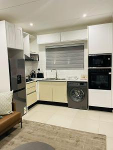 een keuken met witte kasten en een wasmachine en droger bij Canvas Lofts 2 – Famona duplex 2-bed - 2311 in Bulawayo