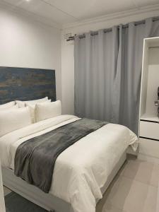 een slaapkamer met een groot bed met witte lakens bij Canvas Lofts 2 – Famona duplex 2-bed - 2311 in Bulawayo
