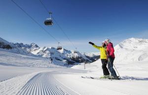 dwoje osób na nartach w śniegu na wyciągu narciarskim w obiekcie Sonne & Schnee in Kühtai w mieście Kühtai