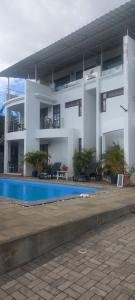 a large white building with a swimming pool in front of it at The Palm Residence in Grand Baie