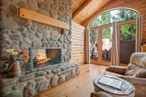 ein Wohnzimmer mit einem Steinkamin in einer Blockhütte in der Unterkunft Adobe Village Villa with Private Patio- Wilderness in Oak Creek