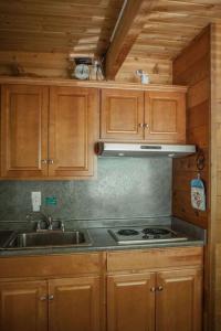 een keuken met houten kasten, een wastafel en een fornuis bij Rustic Cabin for 2 in Oak Creek Cabin - WILD ROSE in Indian Gardens