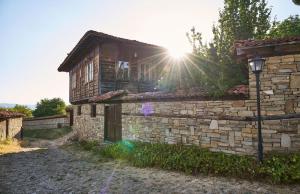 een stenen gebouw met de zon erachter die schijnt bij Радева къща Жеравна in Zheravna