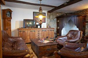 een woonkamer met lederen stoelen en een televisie bij Радева къща Жеравна in Zheravna