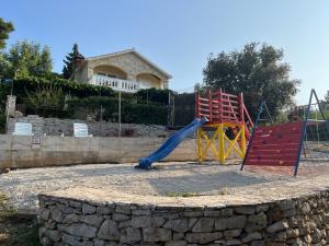 a playground with a slide and two chairs in front of a house at Holiday house Ivko - Korcula in Vela Luka