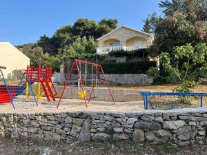 a playground in front of a stone wall at Holiday house Ivko - Korcula in Vela Luka