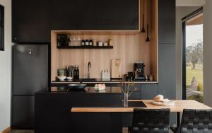 a kitchen with black cabinets and a table with chairs at 8 Paddocks Chalet Four in Cowaramup