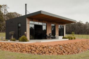 a small black house with a table and chairs at 8 Paddocks Chalet Four in Cowaramup