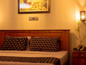 a bed with two pillows and a picture on the wall at BREATHE Collections Habaraduwa in Habaraduwa