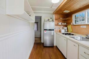 una cucina con frigorifero in acciaio inossidabile e pareti in legno di 2-Bedroom Cottage #3 - Sugar Pine a Gravenhurst
