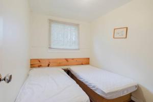 two beds in a small room with a window at 2-Bedroom Cottage #5 - Lodgepole Pine in Gravenhurst