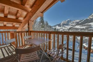 une table et des chaises sur un balcon avec des montagnes dans l'établissement Refuge Les Faitières F7, au Grand-Bornand