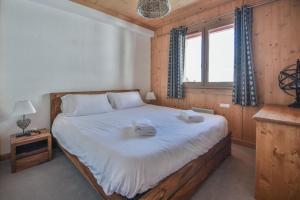une chambre avec un grand lit avec deux serviettes dessus dans l'établissement Refuge Les Faitières F7, au Grand-Bornand