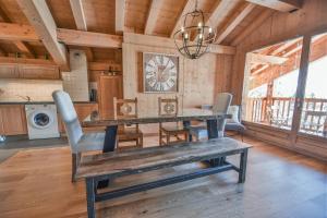 une salle à manger avec une table, des chaises et une horloge dans l'établissement Refuge Les Faitières F7, au Grand-Bornand