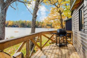 a grill on a wooden deck next to a lake at Studio Cottage #8 - Jack Pine in Gravenhurst