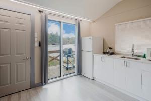 eine Küche mit weißen Schränken und einer Glasschiebetür in der Unterkunft Studio Cottage #9 - Virginia Pine in Gravenhurst
