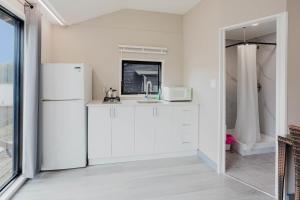 a white kitchen with a sink and a refrigerator at Studio Cottage #9 - Virginia Pine in Gravenhurst