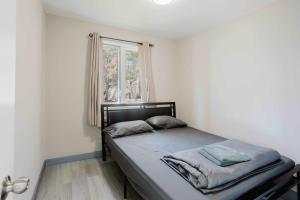 un lit dans une chambre avec une fenêtre dans l'établissement 2-Bedroom Cottage #10 - Pitch Pine, à Gravenhurst