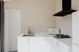 une cuisine blanche avec un évier et un micro-ondes dans l'établissement 2-Bedroom Cottage #10 - Pitch Pine, à Gravenhurst