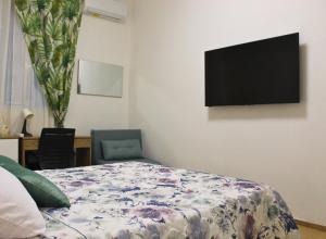una camera da letto con un letto e una TV a schermo piatto di Garden Suite Milano - Vero Gioiello con Giardino a 5 minuti da Mediaset e San Raffaele a Cologno Monzese