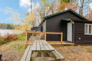 a black cabin with a wooden porch and a deck at 2-Bedroom Cottage #11 - Red Pine in Gravenhurst