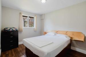 Schlafzimmer mit einem Bett mit einem Kopfteil aus Holz und einem Fenster in der Unterkunft Pine Lake 3-Bedroom Cottage #12 - The Gallery in Gravenhurst