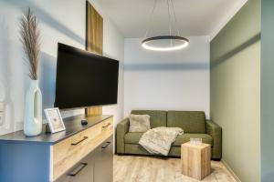 a living room with a green couch and a flat screen tv at Sattler Living Apartments in Ebbs